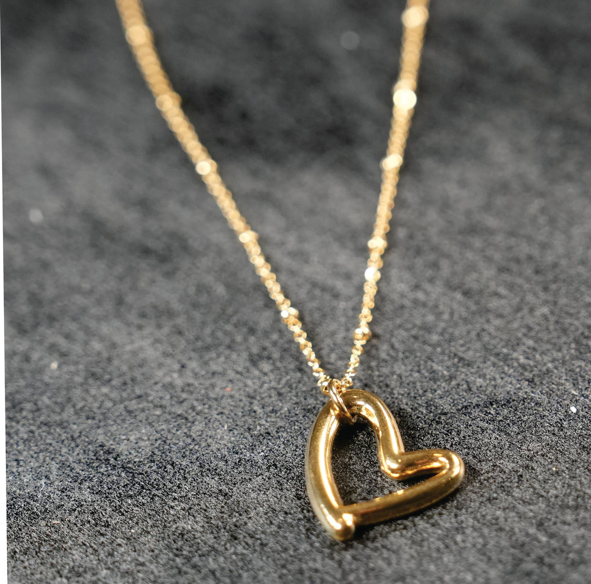 SMITTEN Gold : Une fine chaîne perlée retenant un pendentif en forme de cœur abstrait