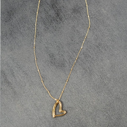 SMITTEN Gold : Une fine chaîne perlée retenant un pendentif en forme de cœur abstrait